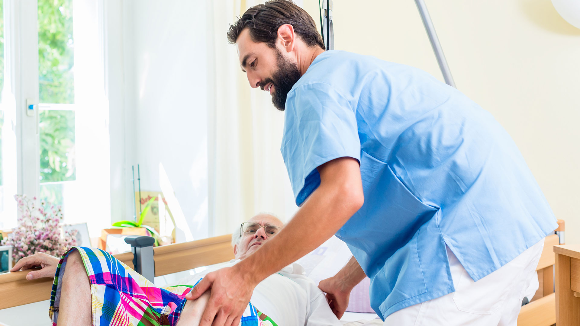 Nurse helping patient getting into bed